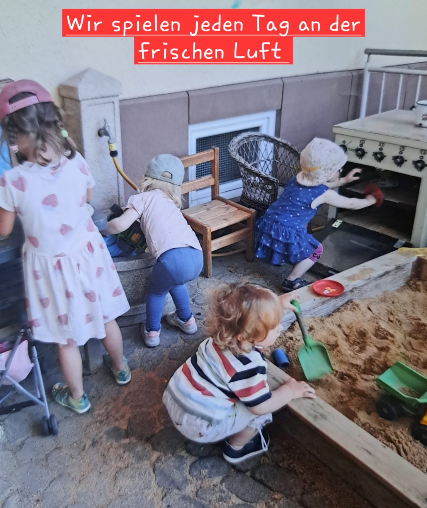 Mehrere Kinder spielen draußen an einer Matschküche und im Sandkasten.